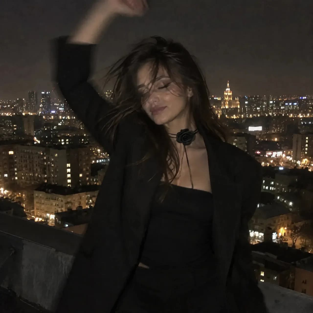 Woman on a rooftop against a city at night